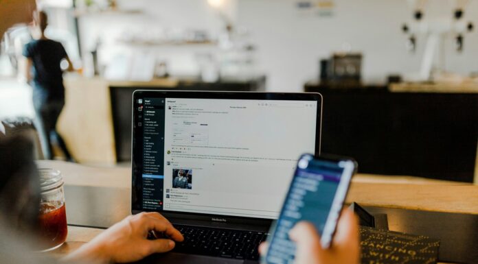 Exploring Communications Degree and Career Opportunities Image of a person sitting in front of their computer and looking at their phone.