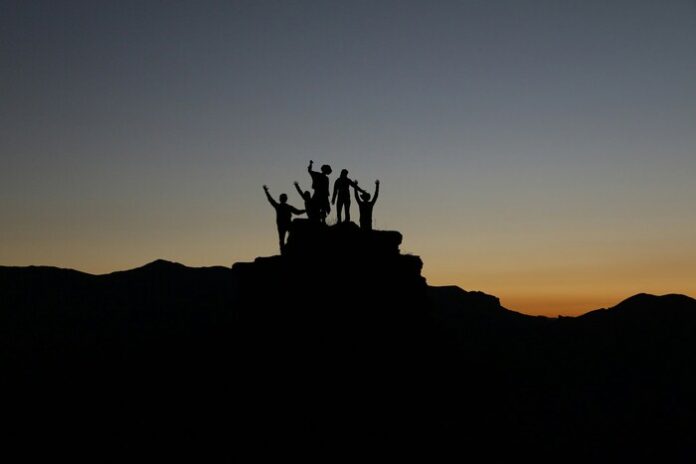 image of individuals, but they are shadows due to the sunset.