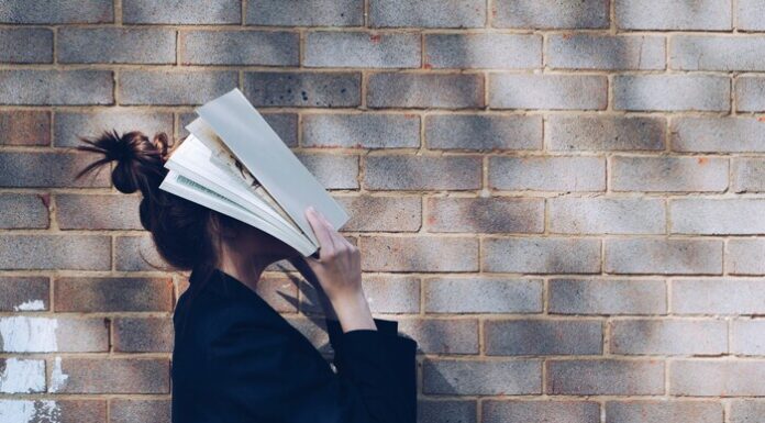 Determining Weekly Study Hours for College Students Image of a woman with a book on her face.
